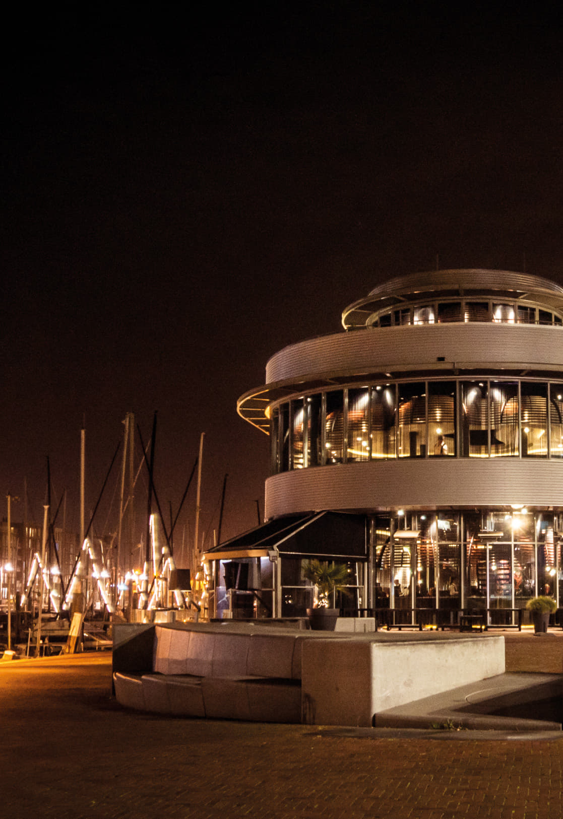 Catch by Simonis contact locatie — het ronde restaurantgebouw bij nacht aan de jachthaven van Scheveningen
